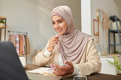 Portrait of attractive Middle Eastern woman wearing hijab sharing her opinion with colleagues during online meeting