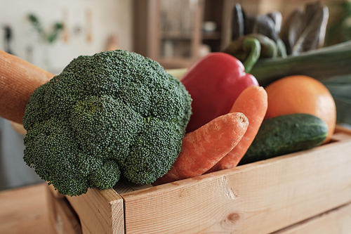 Close-up of fresh vegetables such as broccoli, carrots, cucumbers and bell pepper in wooden box