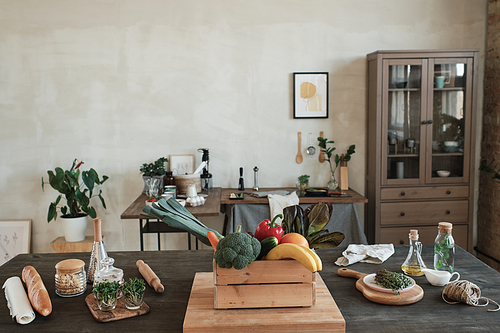Modern kitchen in minimalistic style furnished with old-fashioned cabinet and tables with healthy food and kitchen utensils