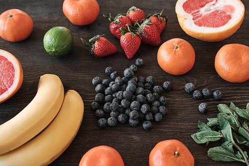 Close-up of bright colorful detox fruits and berries on dark wooden table, ingredients for smoothie