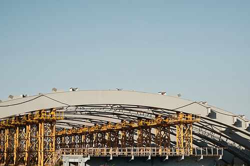 Unfinished city bridge: yellow metal frames supporting arch structure