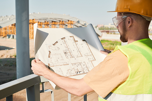 Construction engineer wearing safety vest and work helmet standing at construction site and working on apartment building project