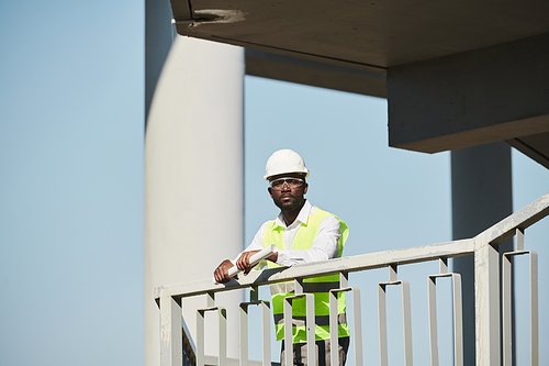 Engineers in protective vests and hardhats standing on balcony at construction site