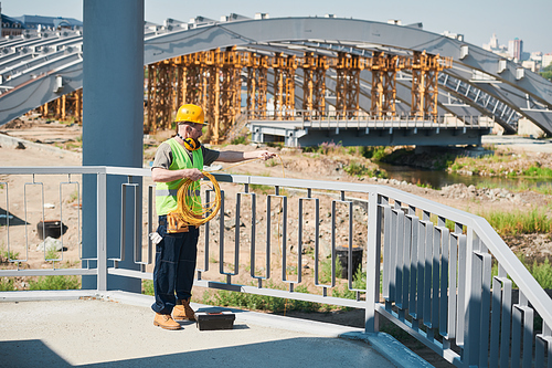 Construction worker wearing hardhat standing on roof of unfinished building, copy space