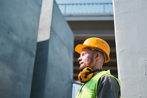 Construction worker wearing hardhat standing on roof of unfinished building, copy space