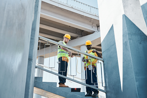 Two construction workers examining metal parts at construction site, copy space