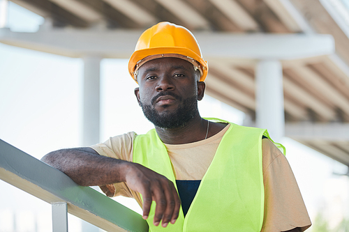 Portrait of smiling construction worker wearing hardhat while posing against concrete wall, copy space