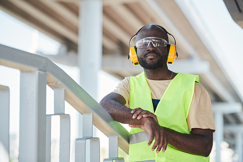 Portrait of young African-American man working at construction site and smiling at camera, copy space