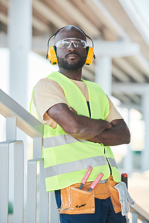 Portrait of smiling construction worker wearing hardhat while posing against concrete wall, copy space