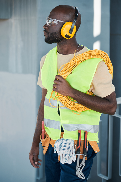 Full length portrait of construction worker standing in elevator and speaking by walkie-talkie giving instructions to crew on site, copy space