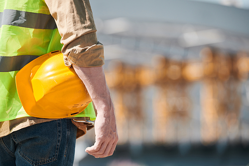 Close up portrait of male construction worker wearing hardhat and looking at camera at construction site, copy space