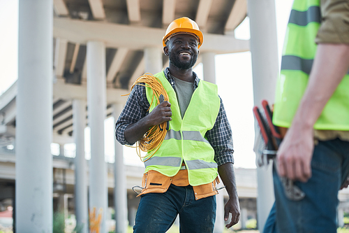 Two workers standing on concrete floor of construction site and discussing project