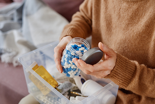 High angle medium close-up shot of woman suffering cold symptoms sitting on sofa with first aid kit