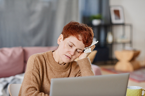 Horizontal medium close-up shot of mature Caucasian woman suffering fever and severer headache resting head on hand