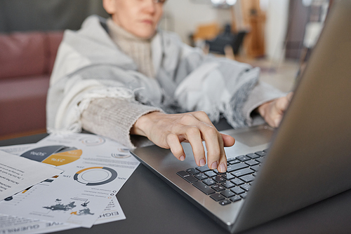 Mature woman suffering influenza sitting at desk in living room at home typing something on laptop