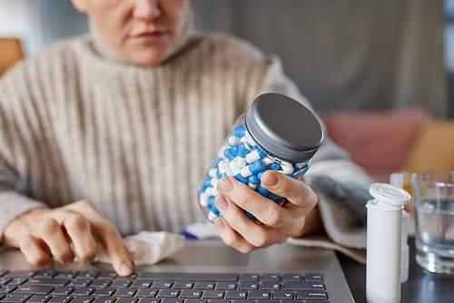 Horizontal selective focus shot of mature Caucasian patient demonstrating pills to doctor during online consultation