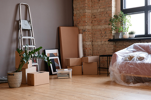 Horizontal no people shot of empty loft living room in modern apartment with boxes, sofa and ladder