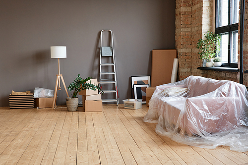 Horizontal no people shot of empty spacious loft living room in modern apartment with boxes, ladder, sofa and various things