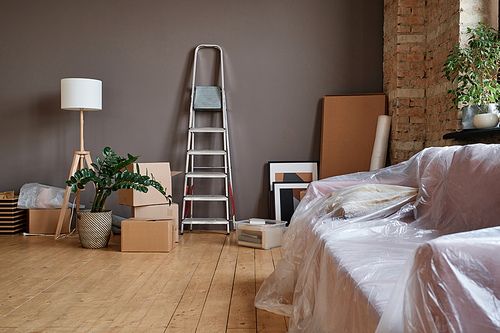 Horizontal no people shot of spacious loft living room interior in modern apartment with boxes unpacked, ladder, sofa and various things