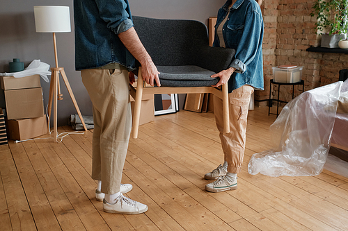 Horizontal shot of unrecognizable man and woman moving to new apartment carrying furniture together