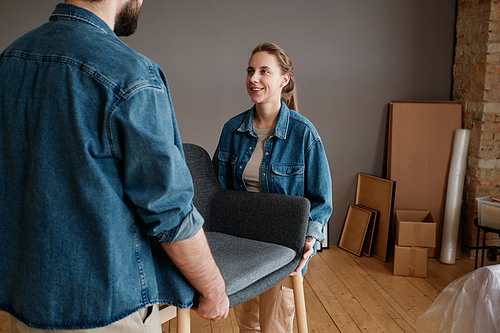 Horizontal shot of modern young man and woman moving to new apartment carrying chairs together