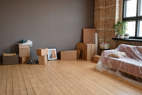 Horizontal no people shot of modern loft living room in spacious apartment with boxes, sofa and various stuff, moving concept