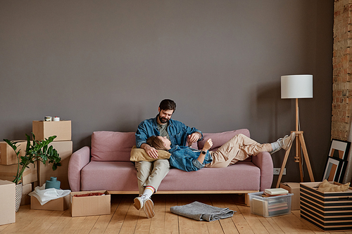 Young man and woman in love relaxing together on sofa in loft living room after moving to new house