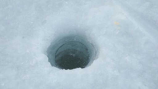 얼음낚시 구멍에 살짝 얼려있는 얼음을 깨는 모습