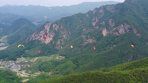 경상북도 문경 산을 배경으로 패러글라이딩을 즐기는 사람들이 하늘을 비행하는