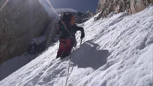 눈이 쌓인 암벽을 등산장비를 착용하고 등반하는 산악인