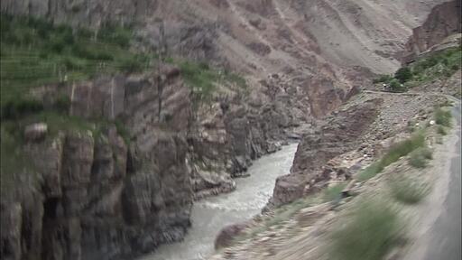 피키스탄 기르기트로 향하는 위험한 높은 비탈길 아래로 계곡물이 세차게 흐르고 좁은 도로를 달리는 자동차