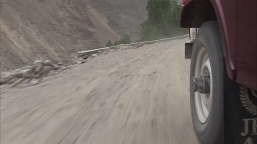 파키스탄 호퍼를 향해 비탈길을 달리는 보라색 트럭 두대가 덜컹 거리며 달리는