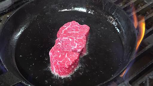 달궈진 후라이팬에 뜨거운 기름에 올린 빨간 소고기를 뒤집어 가며 굽는