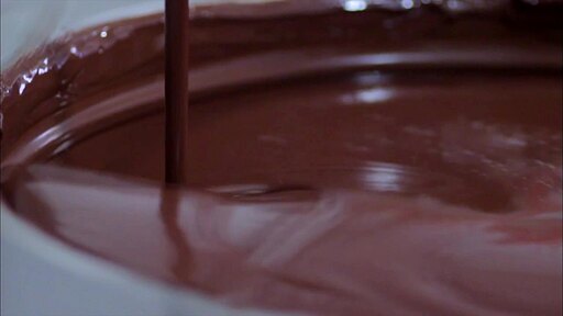 부드럽게 녹은 초콜릿이 회전하는 통에 떨어지고 스푼으로 휘졌는