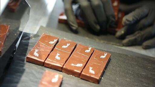 네모 모양으로 완성된 조각 초콜릿을 포장하기 위해 쌓고 있는 장갑 낀 손
