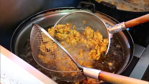끓는 기름에 잘게 잘려진 닭고기를 튀기고 완성된 치킨을 종이에 담아서 포장하는