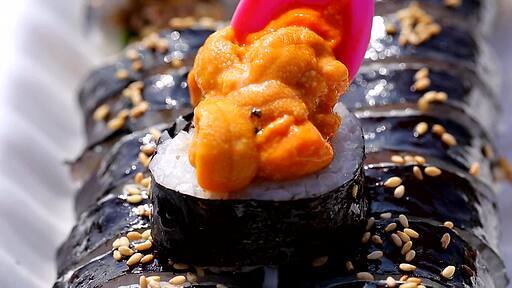 한국음식 김밥위에 주황색 성게 알을 올리는