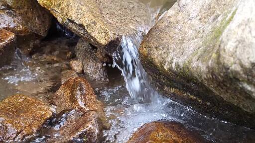 바위 틈으로 깨끗한 물이 떨어지는 냇가에 발을 담그고 있는 모습