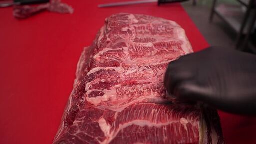 한우 덩어리를 칼로 손질해서 구이용 고기를 포장하는 손