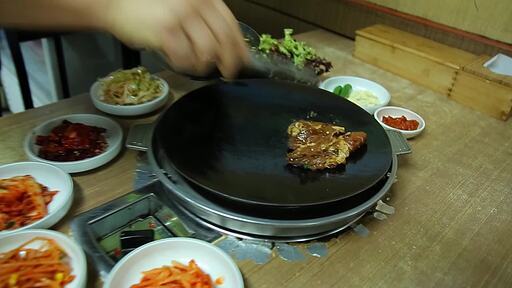 한국 음식 양념 돼지갈비를 양념을 뿌리면서 주물 그리들 위에 올리고 굽는