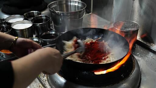 뜨거운 웍에 양파와 고추가루를 넣고 볶다가 육수를 넣고 끓여 짬뽕을 완성해 내는